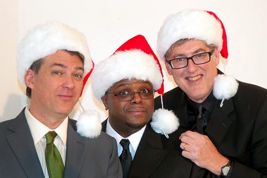 Three men wearing Santa hats smiling.