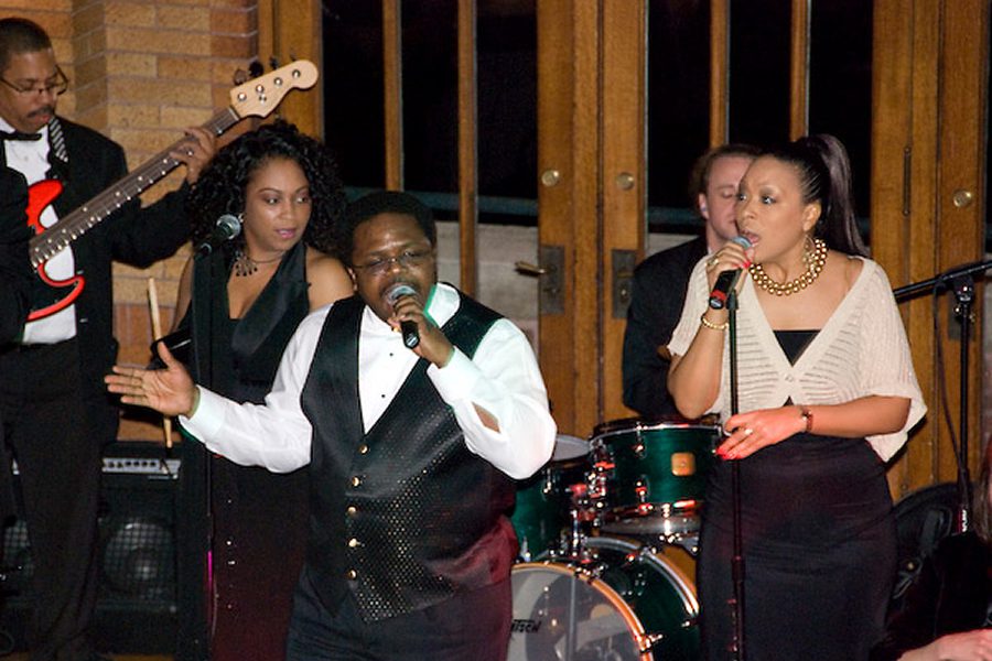 Band performing with singers and musicians on stage.