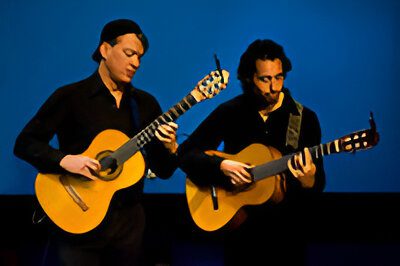 Two musicians playing acoustic guitars on stage.