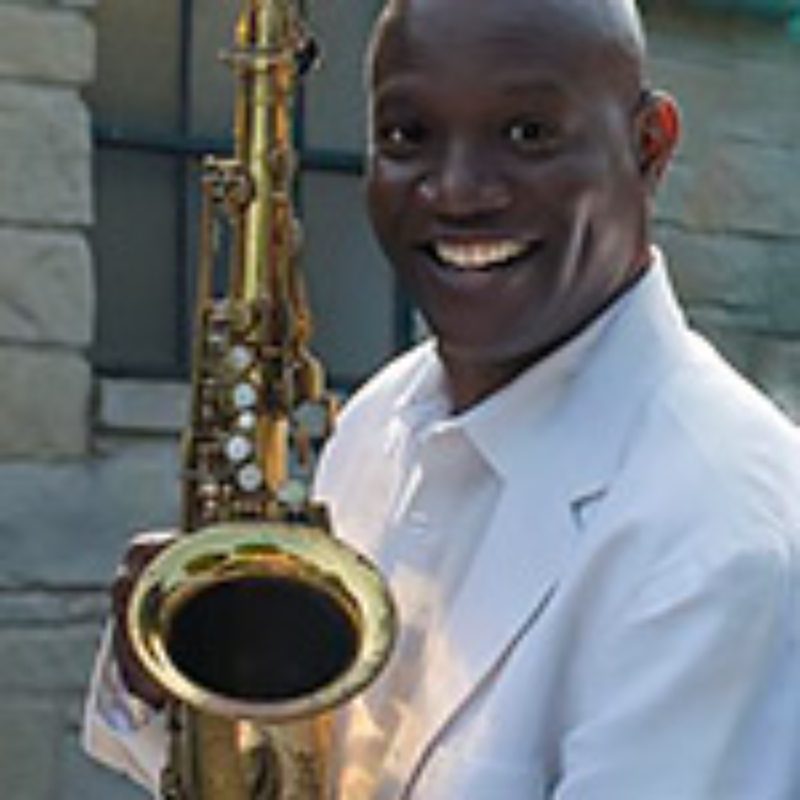 Man smiling while holding a saxophone.