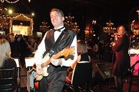 Musician playing guitar at lively indoor event.