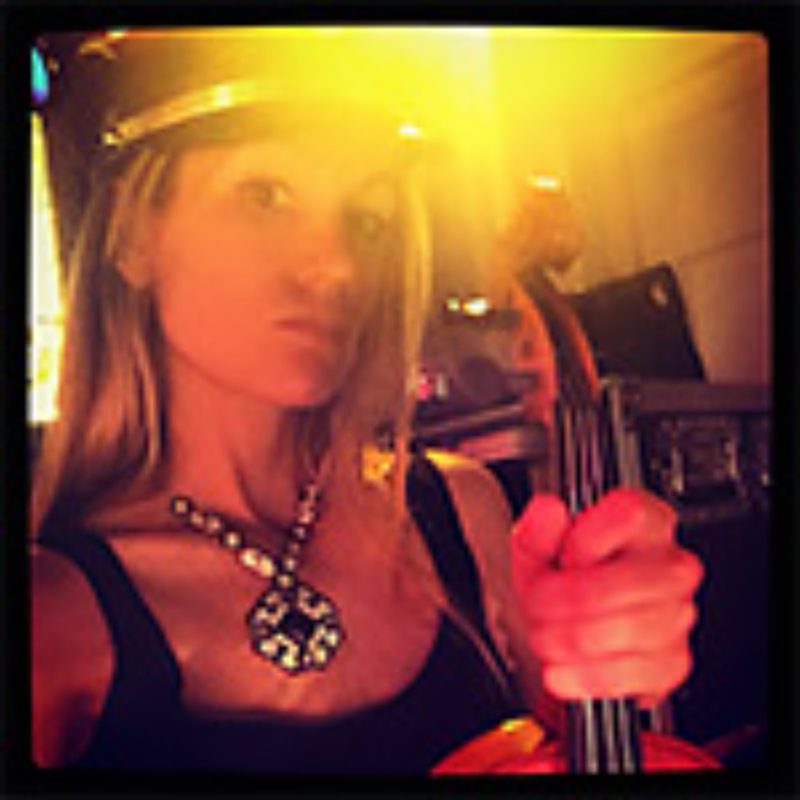 Woman with violin under bright lighting.