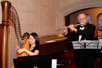 Harpist and flutist performing at event.