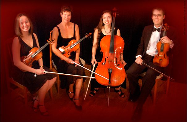 String quartet seated with instruments, smiling.